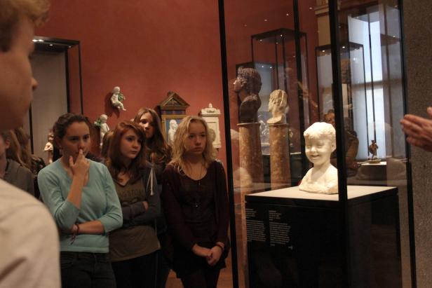 Eine Gruppe von Jugendlichen betrachtet Skulpturen in einem Museum.