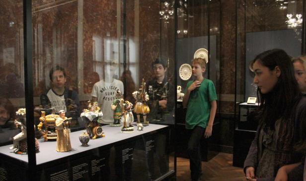 Besucher betrachten eine Vitrine mit historischen Figuren und Objekten in einem Museum.