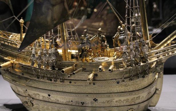Ein detailreiches Modell eines goldenen Segelschiffs mit Kanonen und Figuren an Deck.
