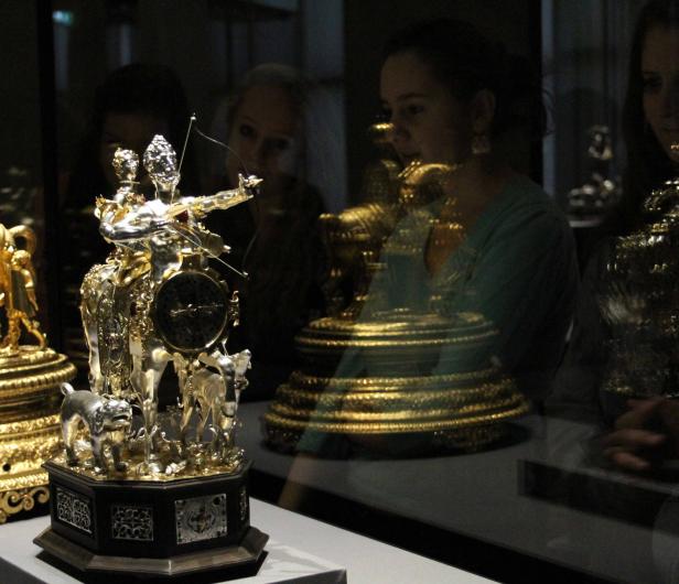 Eine kunstvolle, goldene Uhr mit Figuren und einem Hund im Museum.