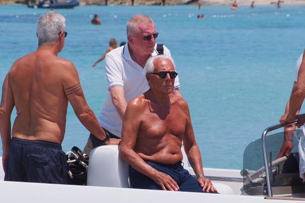 Giorgio Armani sitzt mit zwei Begleitern auf einem Boot.