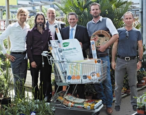 Eine Gruppe von sechs Männern posiert mit einem Einkaufswagen voller Gartenzubehör.