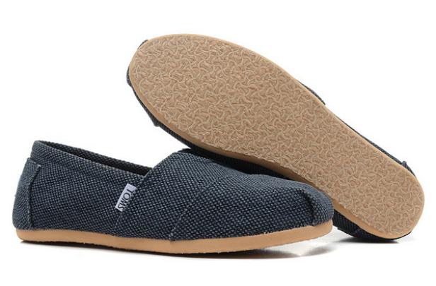 Ein Paar blaue TOMS Schuhe, einer davon mit der Sohle nach oben.