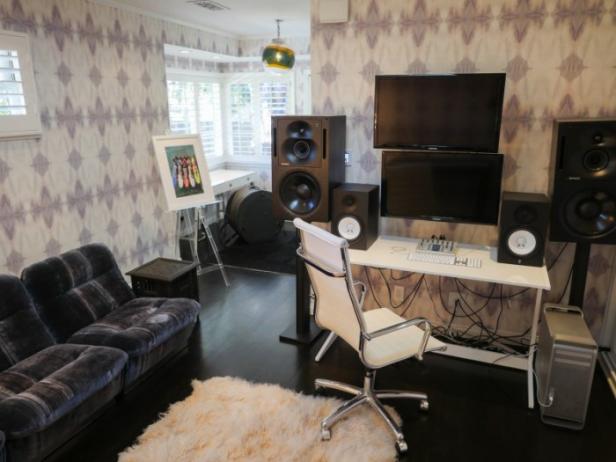 Ein Studio mit einem Schreibtisch, Monitoren, Lautsprechern und einem Sofa.