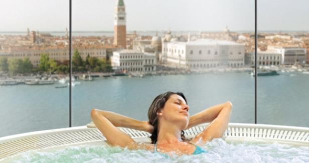 Eine Frau entspannt in einem Whirlpool mit Blick auf Venedig.