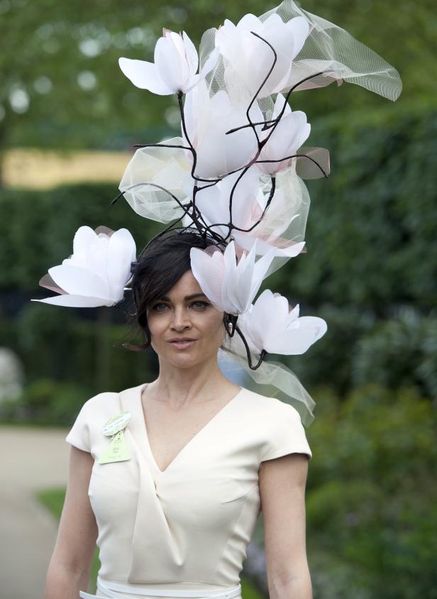 Eine Frau mit einem extravaganten Hut mit weißen Blüten und Schleier.