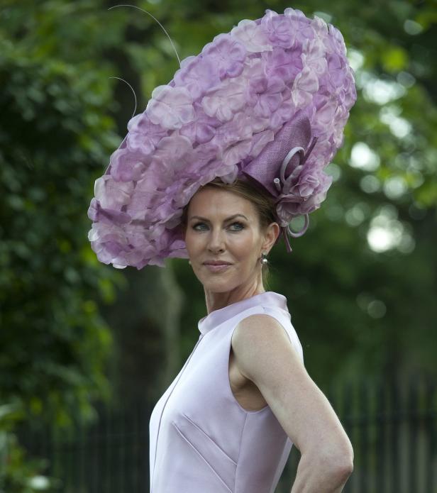 Eine Frau mit einem großen, lilafarbenen Hut und einem passenden Kleid.