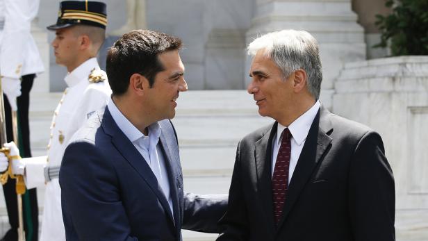 Zwei Männer in Anzügen unterhalten sich vor einem Wachmann.