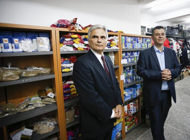 Zwei Männer in Anzügen stehen vor Regalen mit Lebensmitteln.