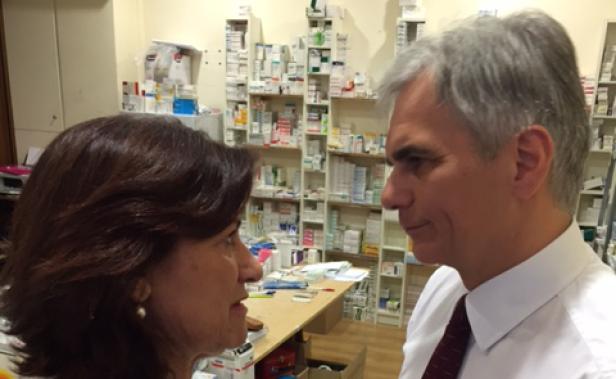 Eine Frau und ein Mann stehen in einer Apotheke und schauen sich an.