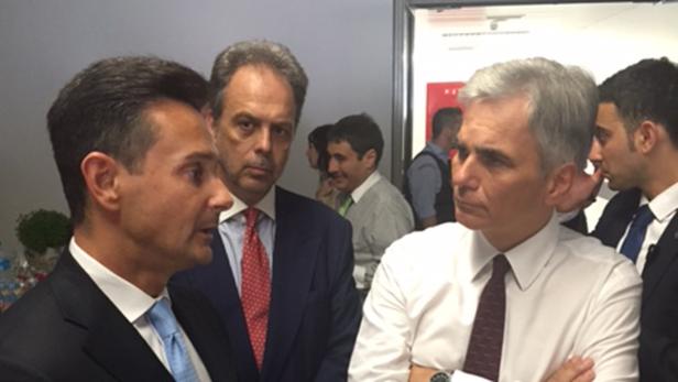 Mehrere Männer in Anzügen unterhalten sich in einem Raum.