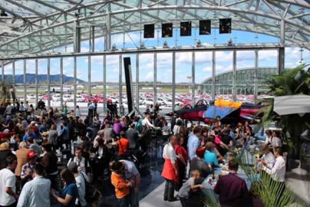 VW up!-Übergabe Hangar 7 Salzburg (c: porsche austria) Eine große Menschenmenge versammelt sich in einem Hangar mit Flugzeugen im Hintergrund.
