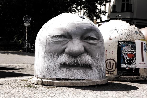 Ein Müllcontainer ist mit dem Gesicht eines alten Mannes mit Bart beklebt.