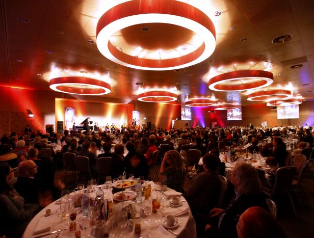 Ein großer Saal mit Tischen und Stühlen, in dem eine Band spielt.