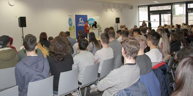 Zahlreiche Zuhörer sitzen bei einer Veranstaltung von UNIQA im Publikum.