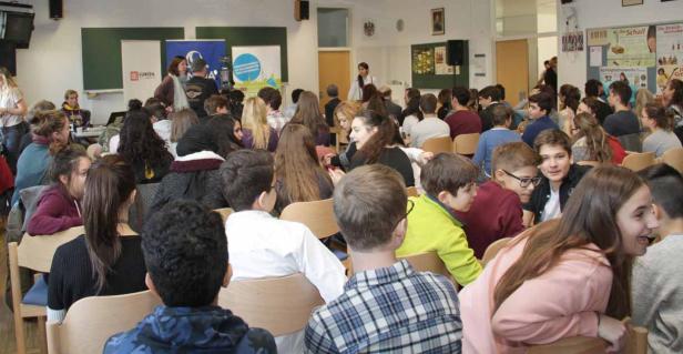 Viele Schüler sitzen in einem Klassenzimmer und hören einem Vortrag zu.