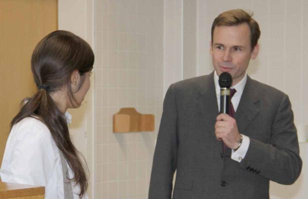 Ein Mann im Anzug spricht in ein Mikrofon, während eine Frau ihm zuhört.