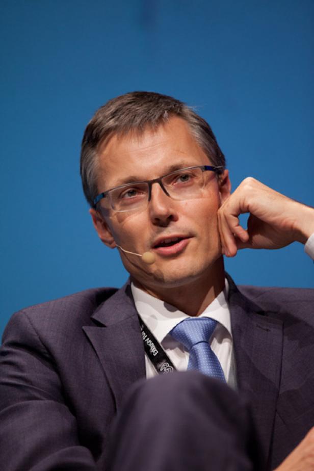 Ein Mann mit Brille und Anzug spricht bei einer Konferenz.