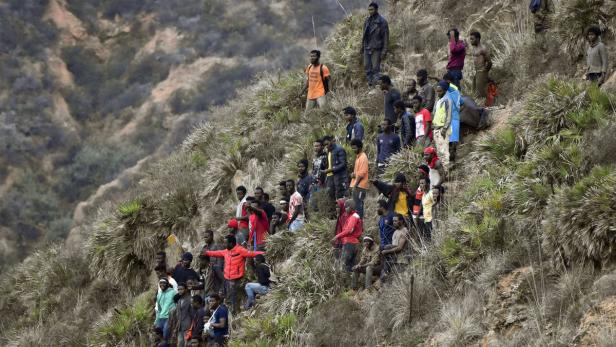 African migrants gather on a hill after crossing a