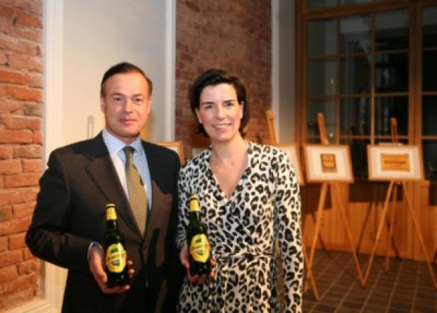 Ein Mann im Anzug und eine Frau im Leopardenkleid präsentieren jeweils eine Flasche Bier.