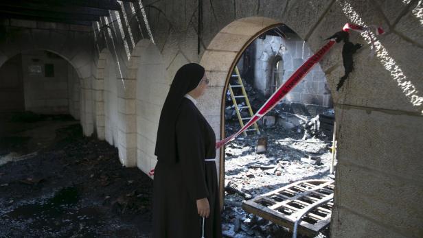 Eine Nonne betrachtet die Schäden in einem durch ein Feuer zerstörten Gebäude.