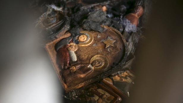 Eine beschädigte, hölzerne Ikone der Geburt Jesu mit Brandspuren.