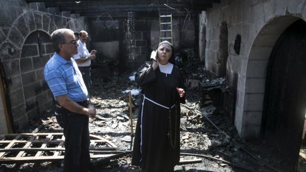 Eine Nonne telefoniert in einem durch ein Feuer beschädigten Gebäude.