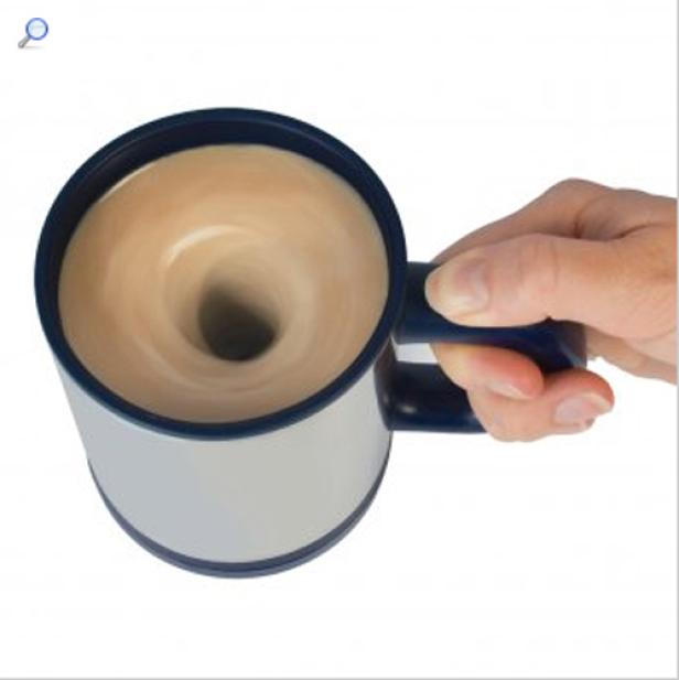 Eine Hand hält eine Tasse, in der sich ein Getränk spiralförmig dreht.