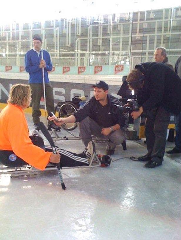 Ein Mann im Schlitten-Eishockey wird interviewt.