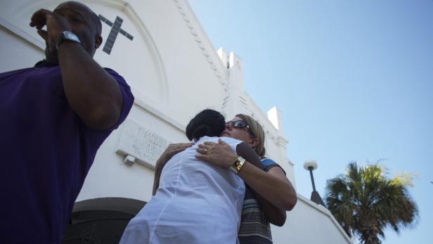 Vor der Emanuel AME Kirche umarmen sich zwei Frauen, während ein Mann weint.