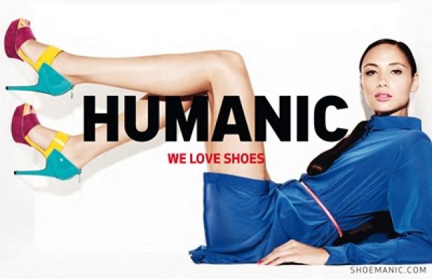Humanic - We Love Shoes - Megaboard - Trojan Gorillas Eine Frau posiert in einem blauen Kleid und farbenfrohen High Heels für eine Humanic-Werbung.