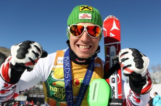 Marcel Hirscher - Ski-As und mutmaßlicher Einfädler Ein lächelnder Skirennläufer mit Medaille und Skiern vor blauem Himmel.