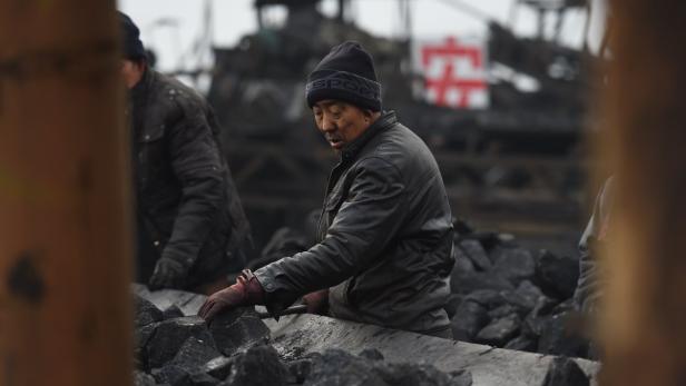 Ein Mann mit Mütze und Handschuhen arbeitet mit Kohle.