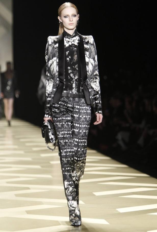 Ein Model in einem schwarz-weiß gemusterten Hosenanzug auf dem Laufsteg.