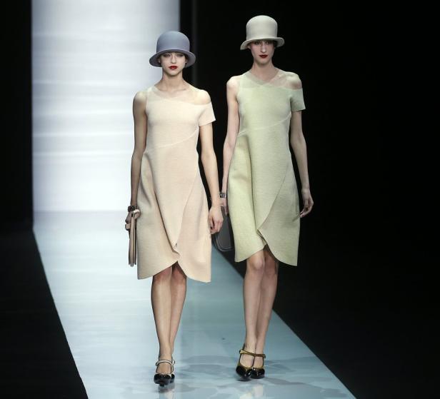 Zwei Models präsentieren Kleider und Hüte auf einem Laufsteg.