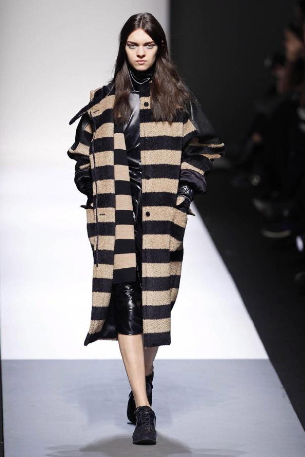 Eine Frau präsentiert einen gestreiften Mantel auf dem Laufsteg.