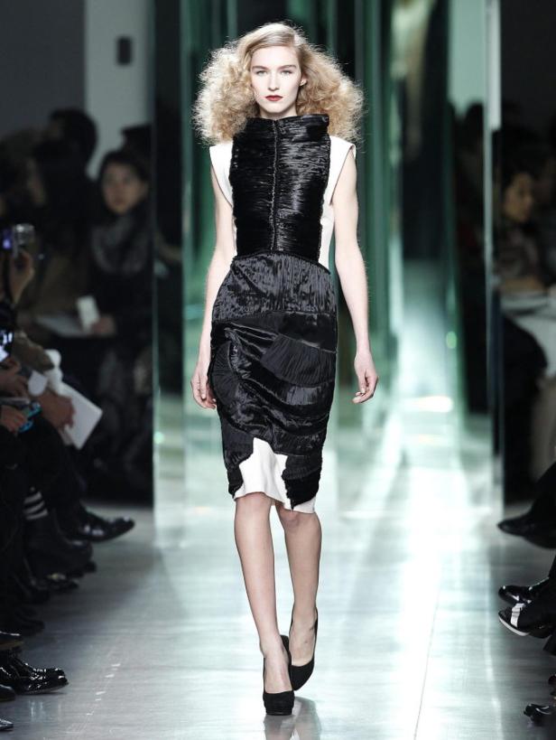 Ein Model präsentiert ein schwarz-weißes Kleid auf dem Laufsteg.