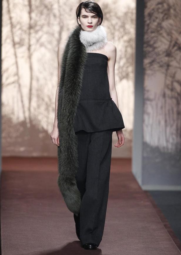 Eine Frau mit dunklen Haaren trägt ein trägerloses Oberteil und eine lange Pelzstola.