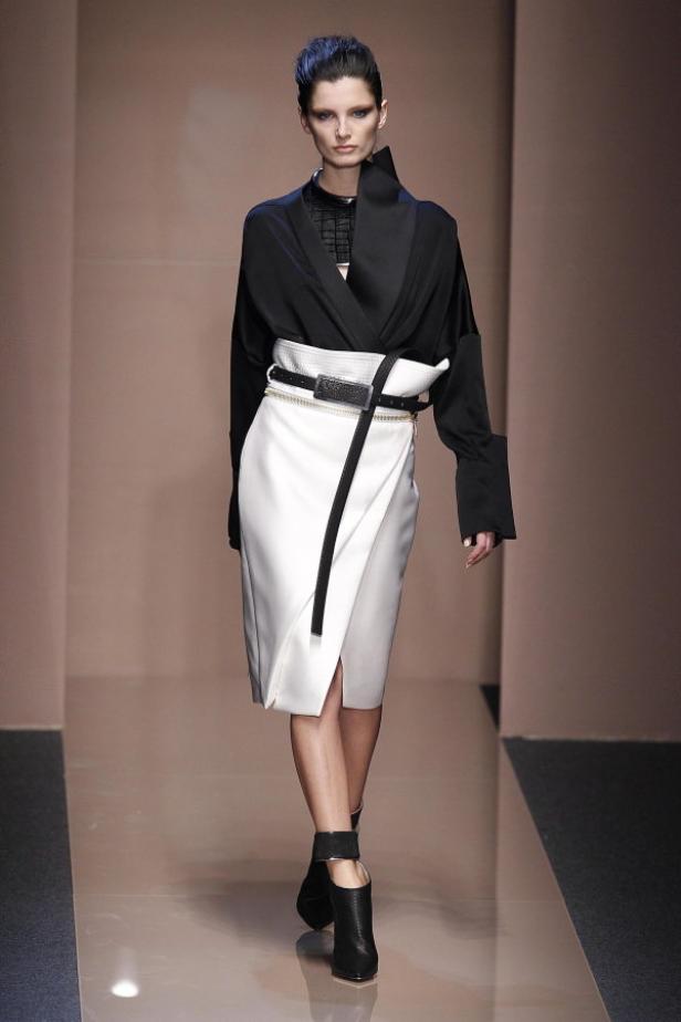 Eine Frau präsentiert ein schwarz-weißes Outfit mit Wickelrock auf dem Laufsteg.