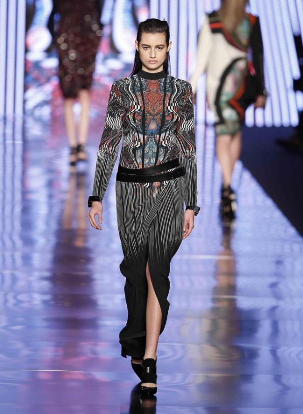 Ein Model präsentiert ein schwarz-weißes Kleid mit auffälligem Muster auf dem Laufsteg.