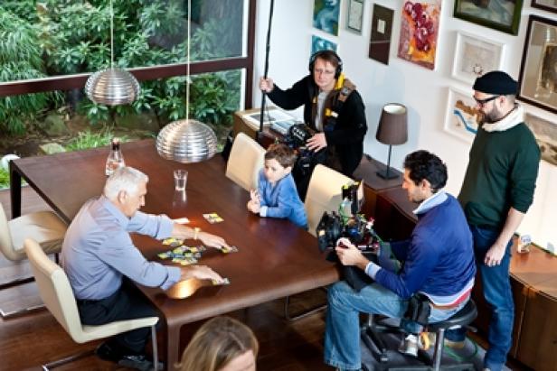 Sky - Film-Kampagne - Rolling Board - Hans Krankl (c: sky austria) Ein älterer Mann und ein Junge sitzen an einem Tisch und spielen Karten, während ein Filmteam sie filmt.