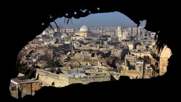 Blick durch eine Öffnung auf eine zerstörte Stadtlandschaft mit einer Moschee im Zentrum.