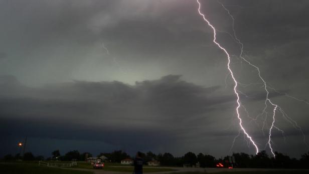 Cloud-to-ground lightning from a tornadic thunders Ein Blitz erhellt den dunklen Himmel über einer ländlichen Gegend.