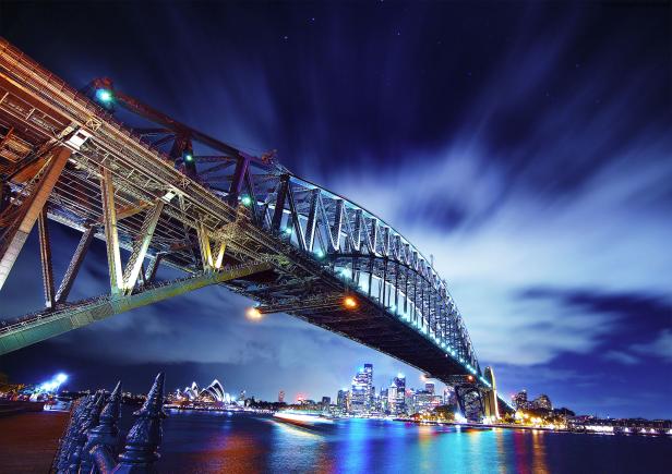 Die beleuchtete Sydney Harbour Bridge überspannt das Wasser bei Nacht.