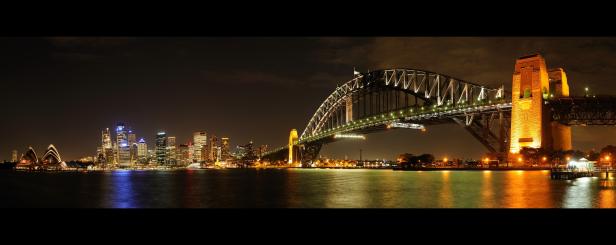 Die beleuchtete Skyline von Sydney mit dem Opernhaus und der Harbour Bridge bei Nacht.
