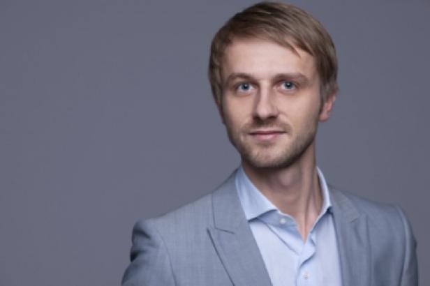 Ein Mann mit blonden Haaren und blauem Hemd trägt ein helles Sakko.
