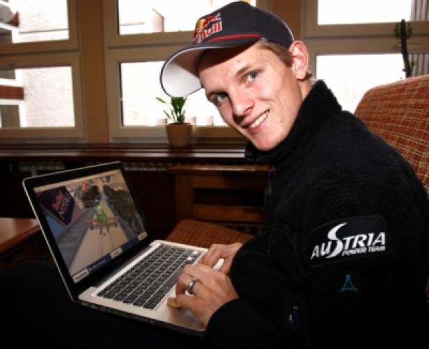 Thomas Morgenstern - Testimonial - Skijumpgiants.at - Red Bull Media House - Greentube (c: GEPA - Luger Walter) Ein Mann mit Red Bull-Kappe sitzt vor einem Laptop und lächelt.