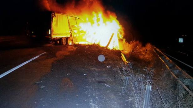 Ein Lastwagen steht in Flammen am Straßenrand.