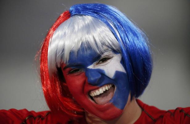 Eine Frau mit rot-weiß-blauer Perücke und Gesichtsbemalung jubelt.