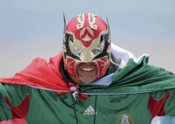 Ein Mann mit einer Luchador-Maske und einem mexikanischen Fußballtrikot lächelt.